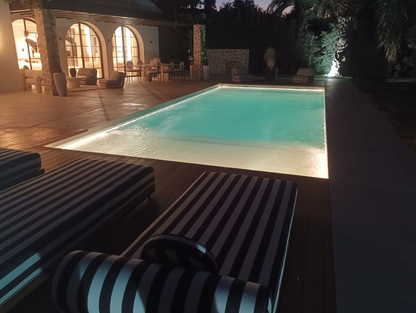 Piscina con iluminación LED perimetral en una villa de noche