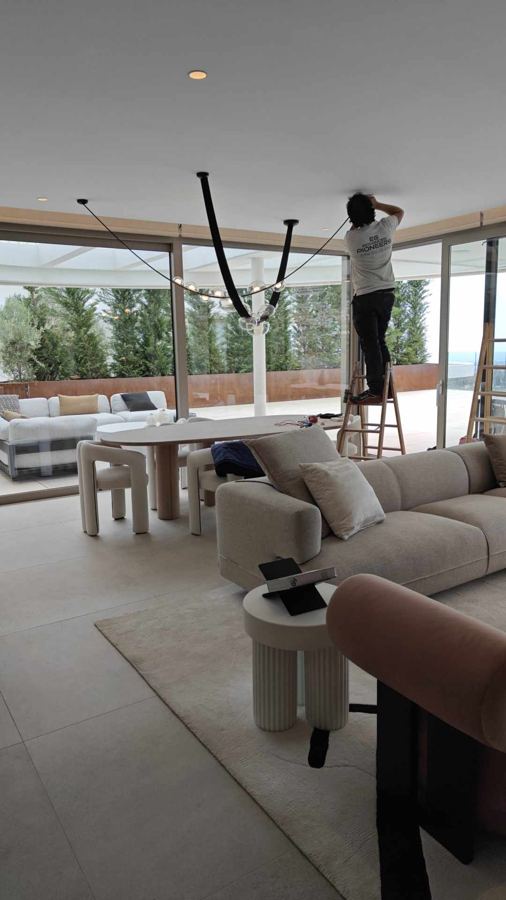 Técnico instalando una lámpara colgante en un salón con vistas